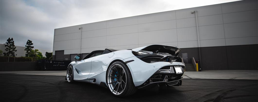 White McLaren sportscar with modifications on an asphalt surface.