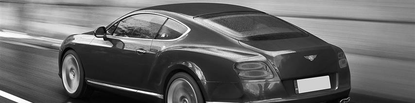 Black and white image of a black Bentley driving through a lit tunnel